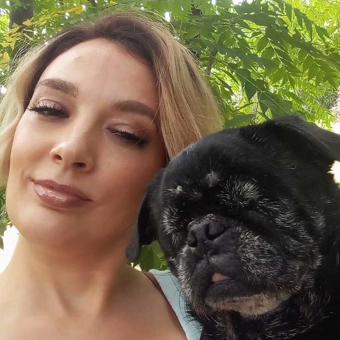 A woman looks at the camera with a small black dog