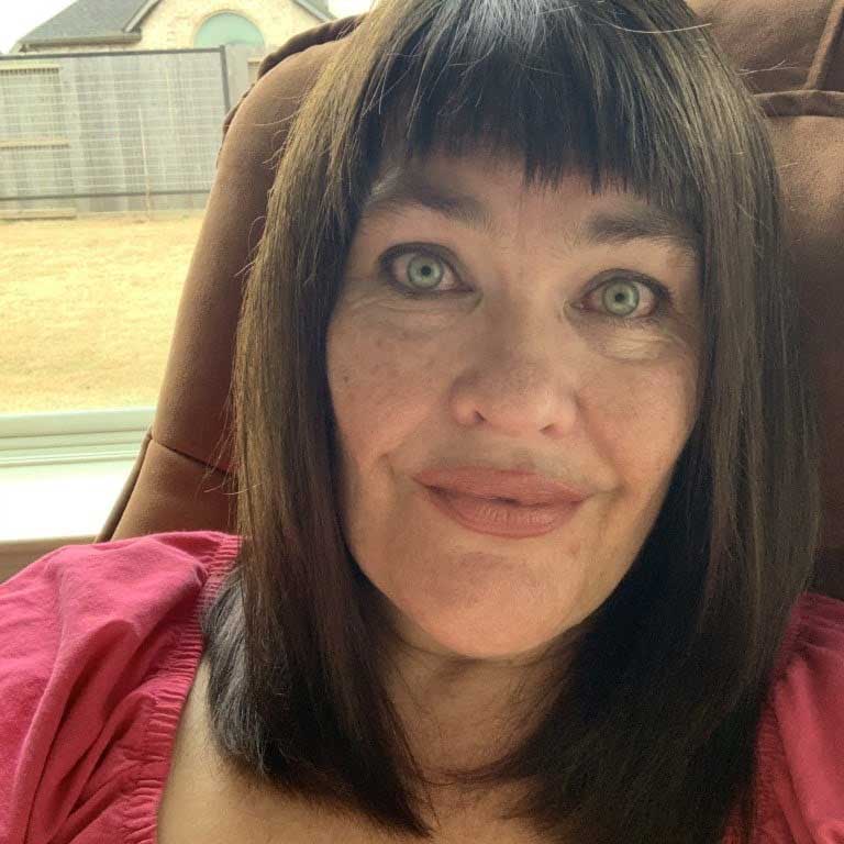 An older woman with dark brown hair smiles at the camera